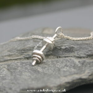 A sterling silver dumbell on a sterling silver chain. There are a total of 6 weights on the dumbell pendant.